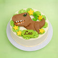 A round birthday cake with white frosting, decorated with a brown fondant T-rex dinosaur, green leaf swirls, yellow star-shaped decorations, a green number 3, and a green plaque spelling 'Leo', shown on a light green background.